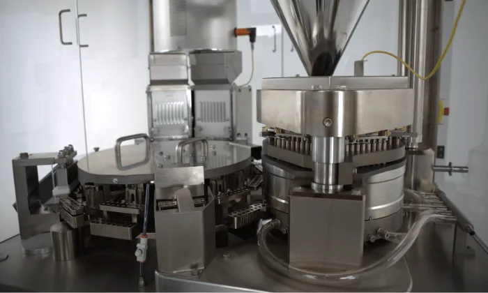 Close-up of automatic encapsulation equipment showing capsule filling station, dosing system, and stainless steel components designed for high-output production.