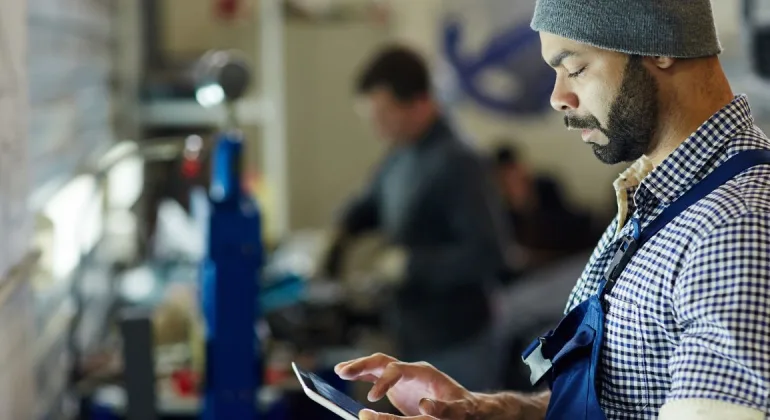 A warehouse technician managing capsule spare parts inventory with a tablet device.