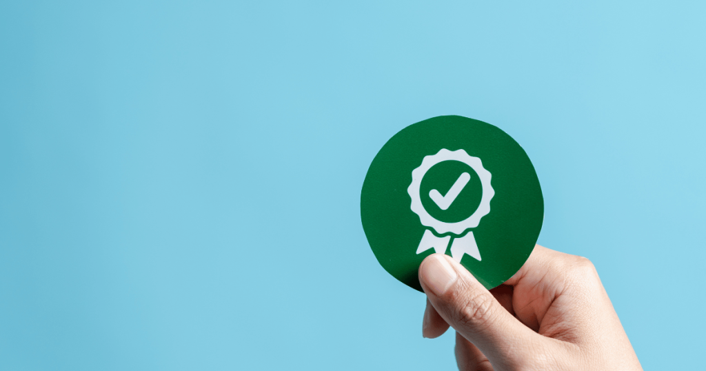 An image of a hand holding a capsule filling regulatory compliance seal-of-approval badge against a blue background.