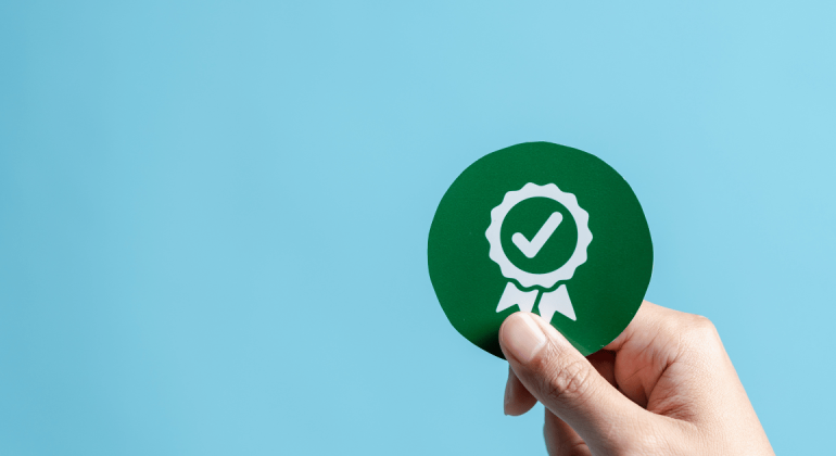 An image of a hand holding a capsule filling regulatory compliance seal-of-approval badge against a blue background.