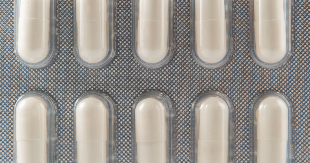 A closeup shot of white filled capsules enclosed in a foil package.