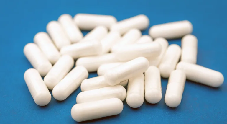 A group of white colored capsules resting on a blue surface.