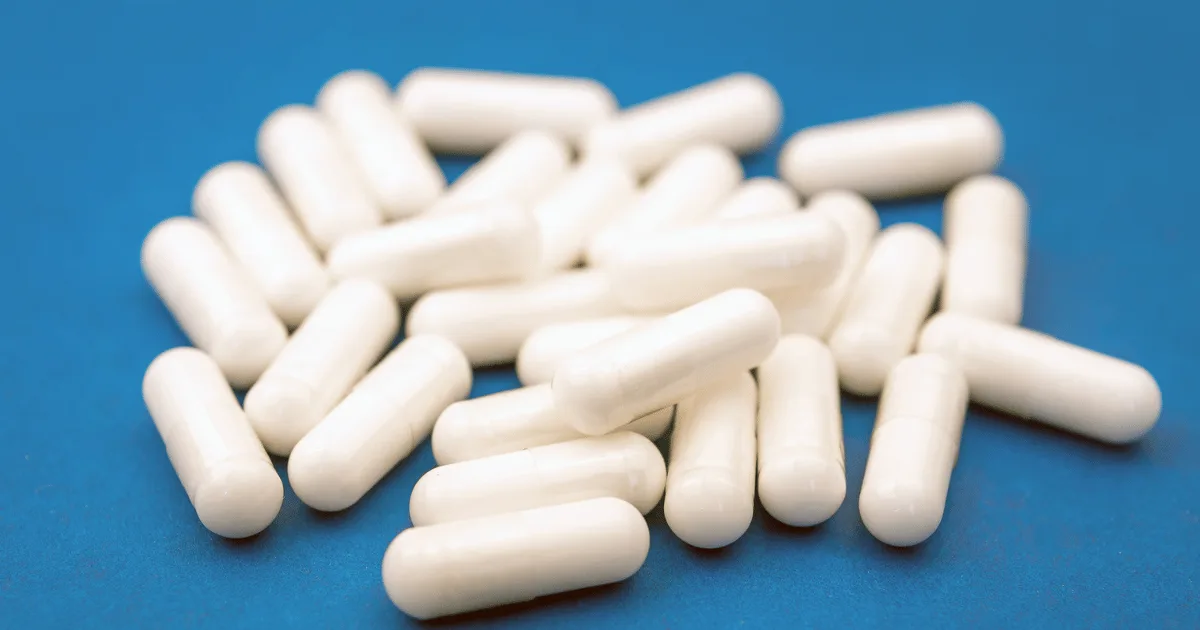 A group of white colored capsules resting on a blue surface.