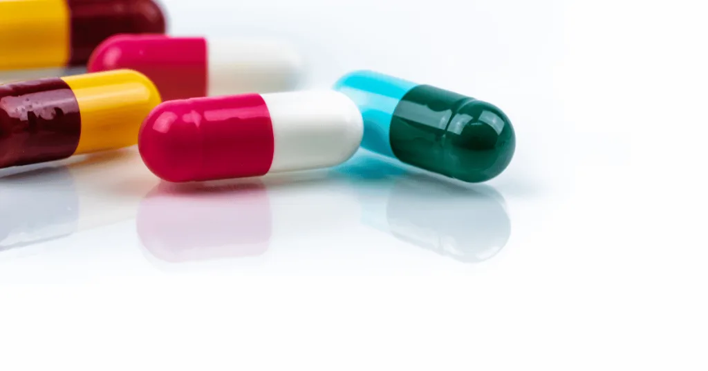 A close-up shot of a group of capsules. They have different colored capsule heads and bodies of white, yellow, green, pink, and blue.